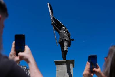 Turister flokker til ny statue i London. Bak står en myteomspunnet kunstner.